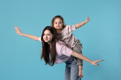 Photo of Portrait of cute sisters on light blue background