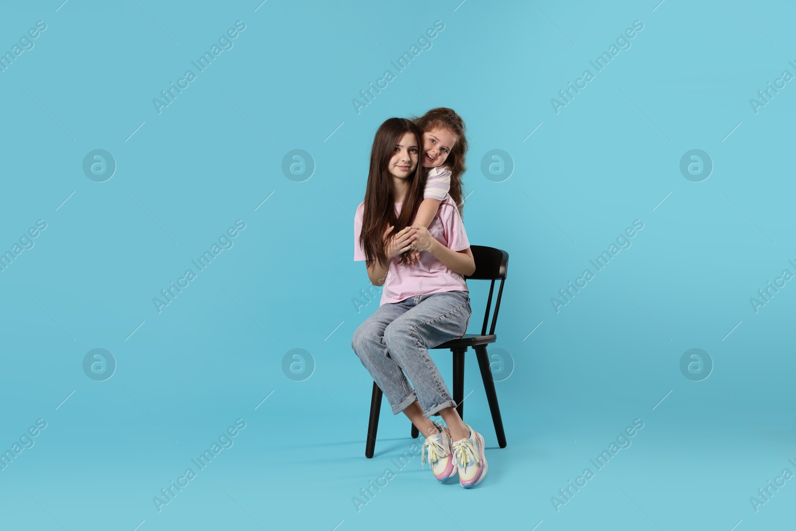 Photo of Portrait of cute sisters on light blue background