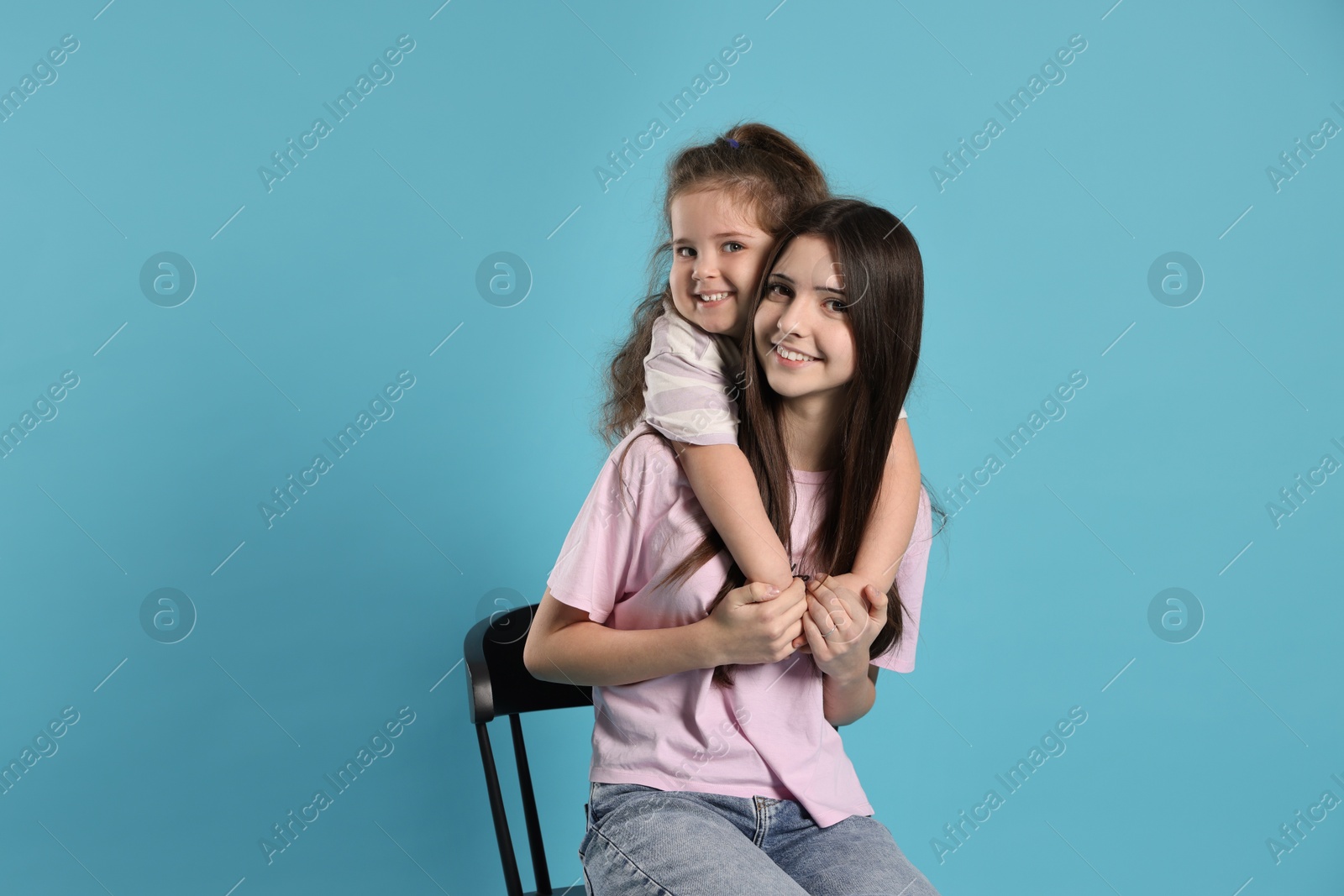 Photo of Portrait of cute sisters on light blue background