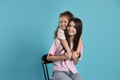 Portrait of cute sisters on light blue background