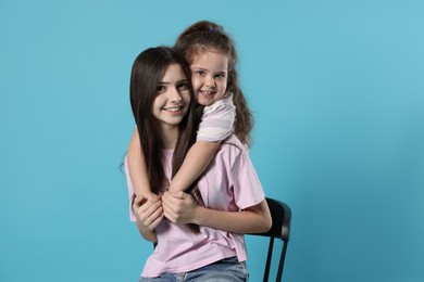 Photo of Portrait of cute sisters on light blue background