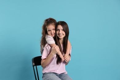 Photo of Portrait of cute sisters on light blue background