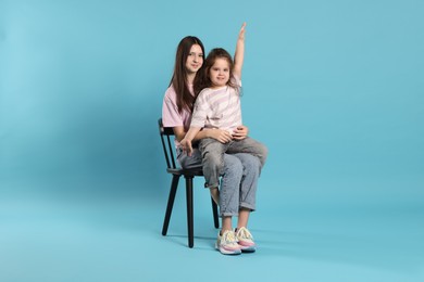 Photo of Portrait of cute sisters on light blue background