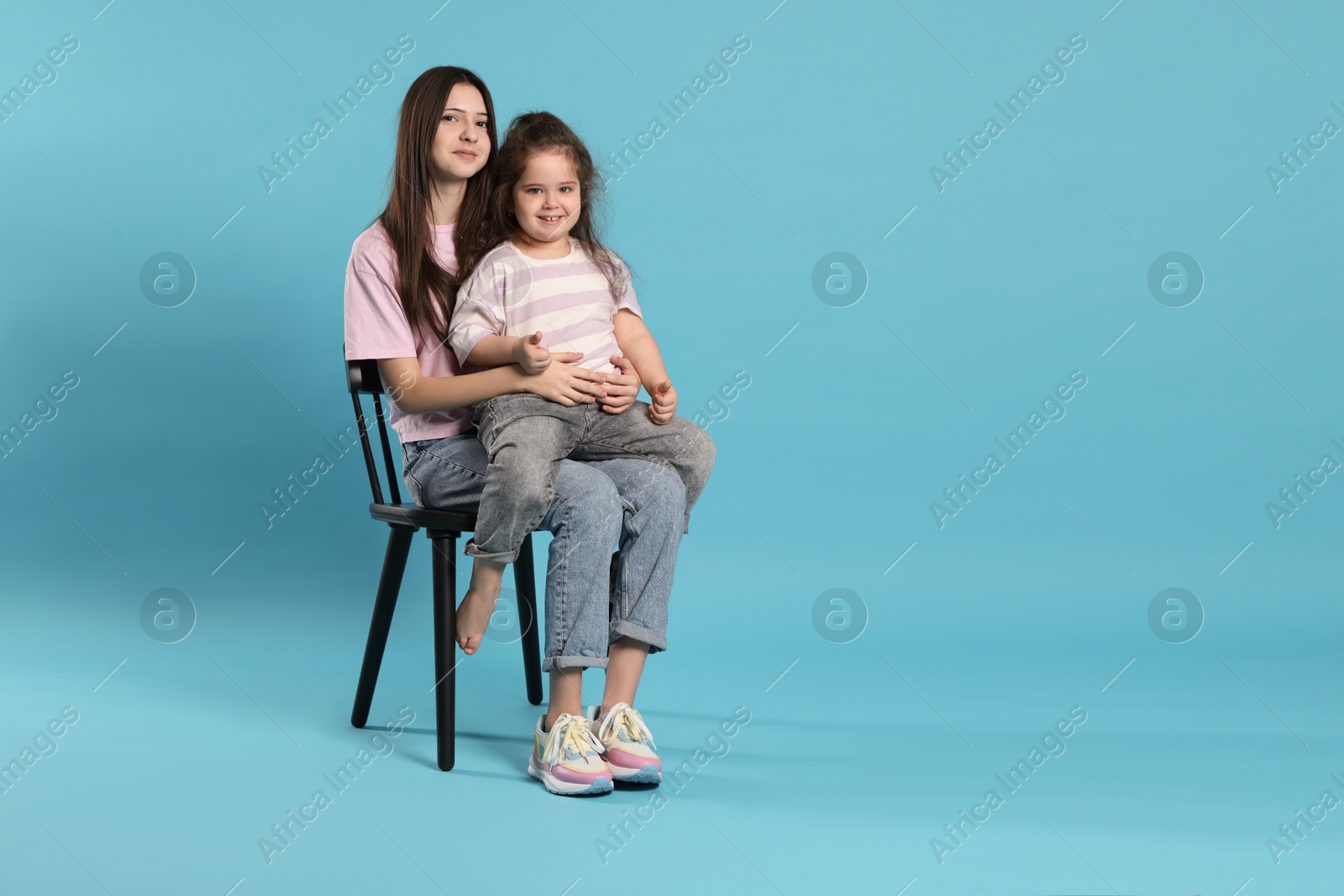 Photo of Portrait of cute sisters on light blue background