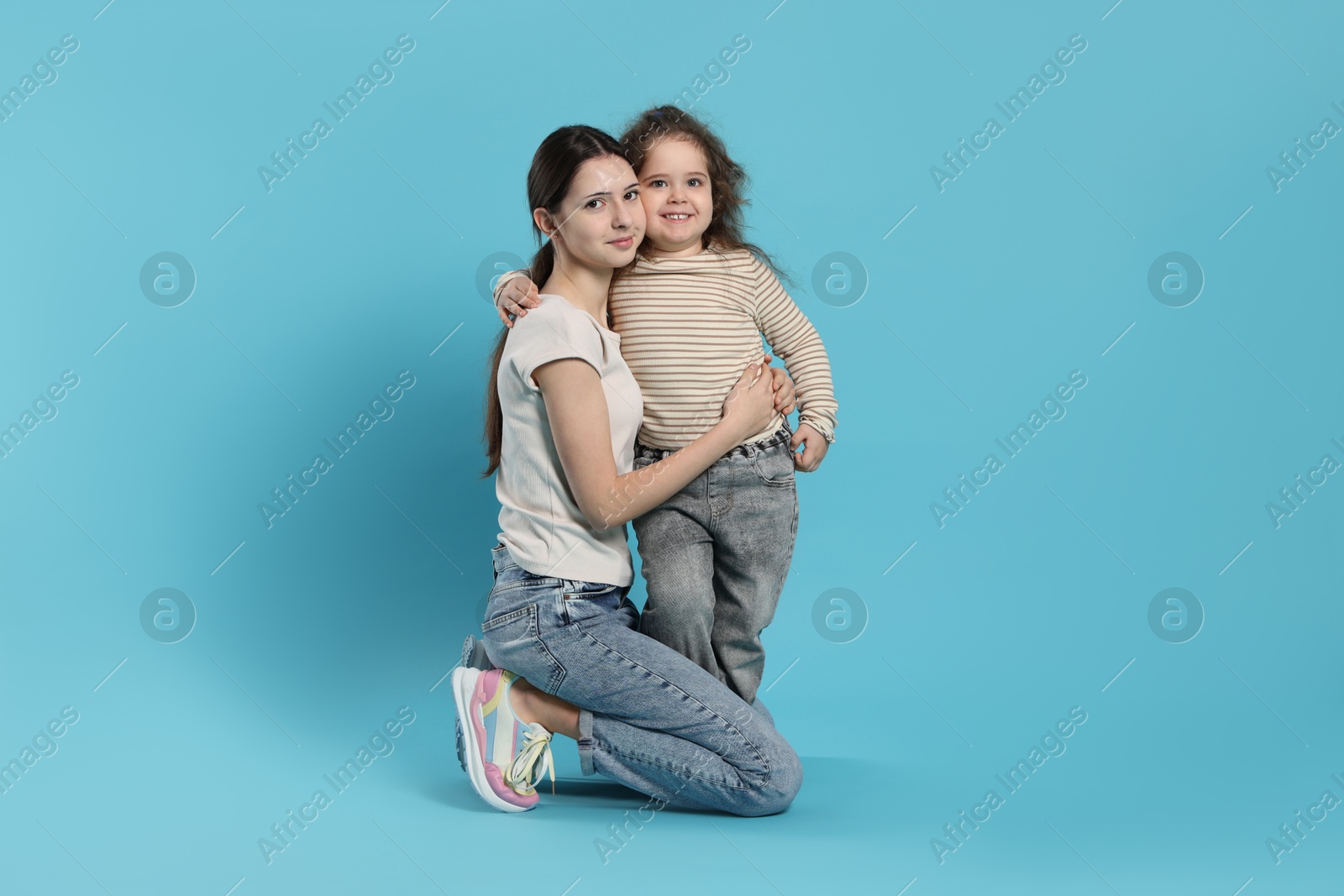 Photo of Portrait of cute sisters on light blue background