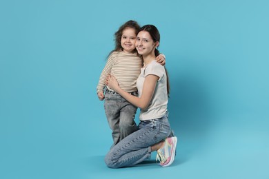 Photo of Portrait of cute sisters on light blue background