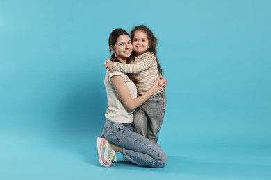 Photo of Portrait of cute sisters on light blue background