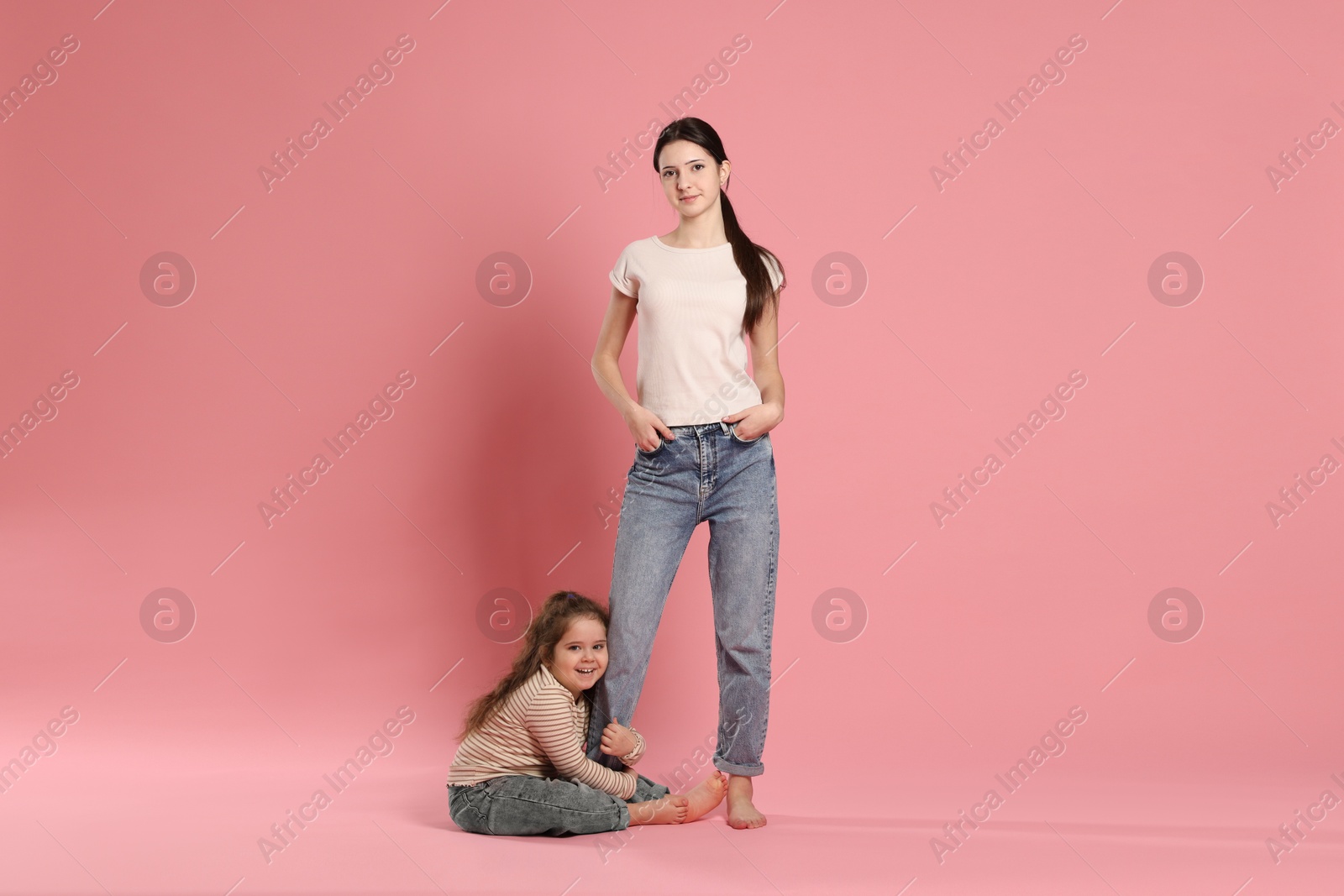 Photo of Portrait of cute sisters on pink background