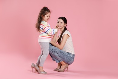 Photo of Cute little girl with lip gloss and her sister on pink background