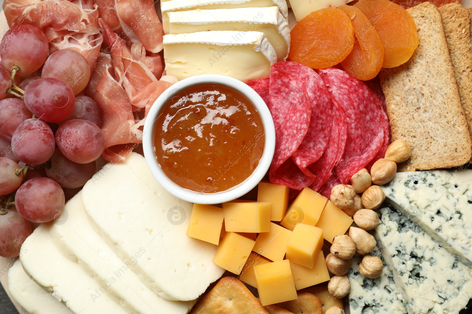 Photo of Different types of cut cheese and other snacks on table, top view