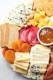 Photo of Different types of cut cheese and other snacks on light textured table, top view