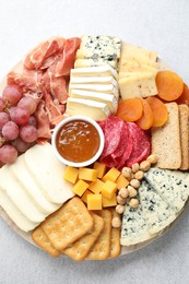 Photo of Different types of cut cheese and other snacks on light textured table, top view