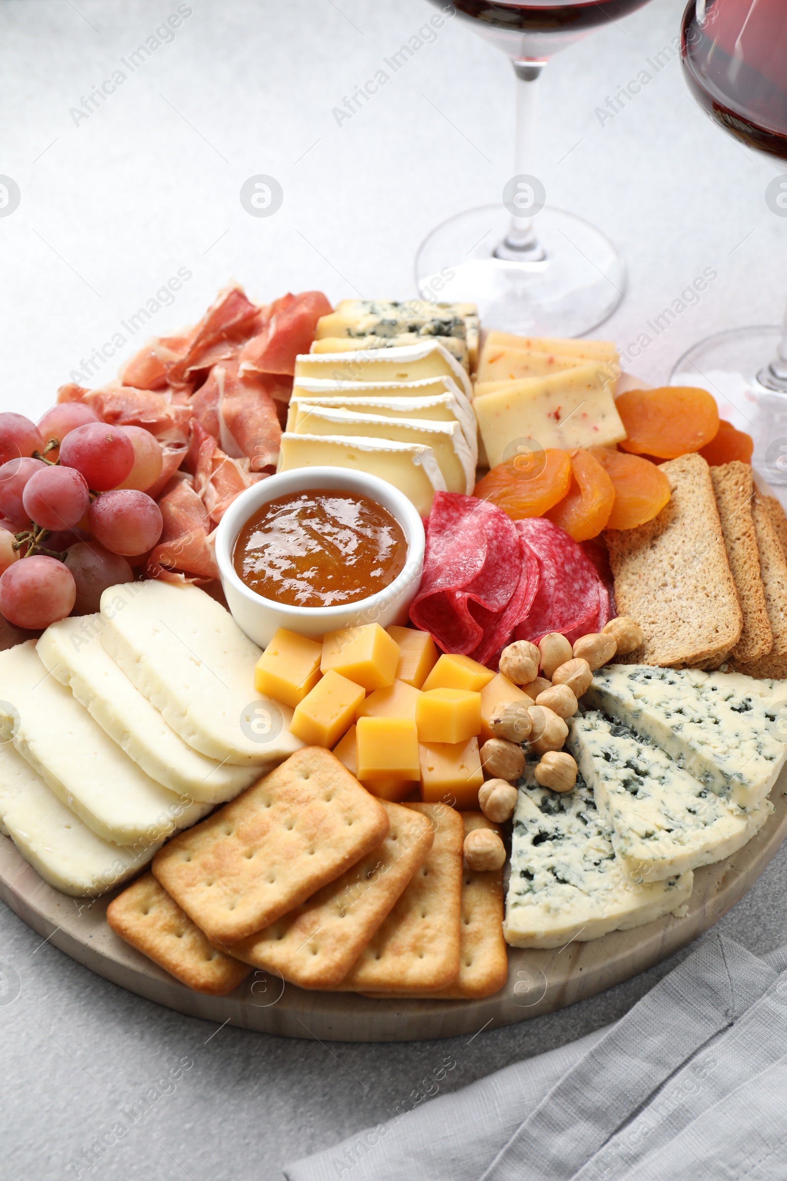 Photo of Different types of cut cheese and other snacks on light textured table