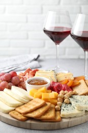 Photo of Different types of cut cheese and other snacks on light textured table, closeup