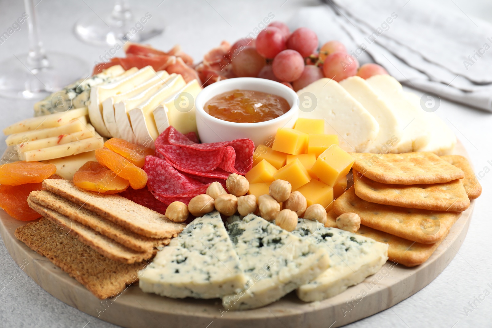 Photo of Different types of cut cheese and other snacks on light textured table, closeup