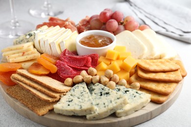 Photo of Different types of cut cheese and other snacks on light textured table, closeup