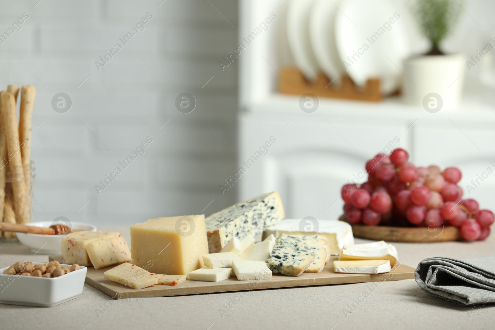 Photo of Different types of cut cheese and other snacks on light textured table indoors