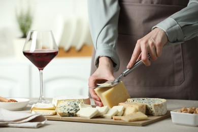 Photo of Woman slicing delicious cheese at light textured table indoors, closeup