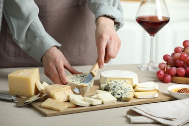 Photo of Woman slicing delicious cheese at light textured table indoors, closeup