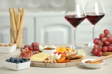 Photo of Different types of cut cheese and other snacks on light textured table, closeup