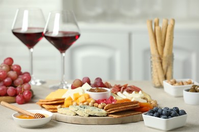 Photo of Different types of cut cheese and other snacks on light textured table, closeup