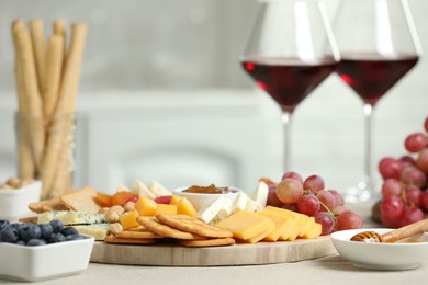 Photo of Different types of cut cheese and other snacks on light textured table, closeup