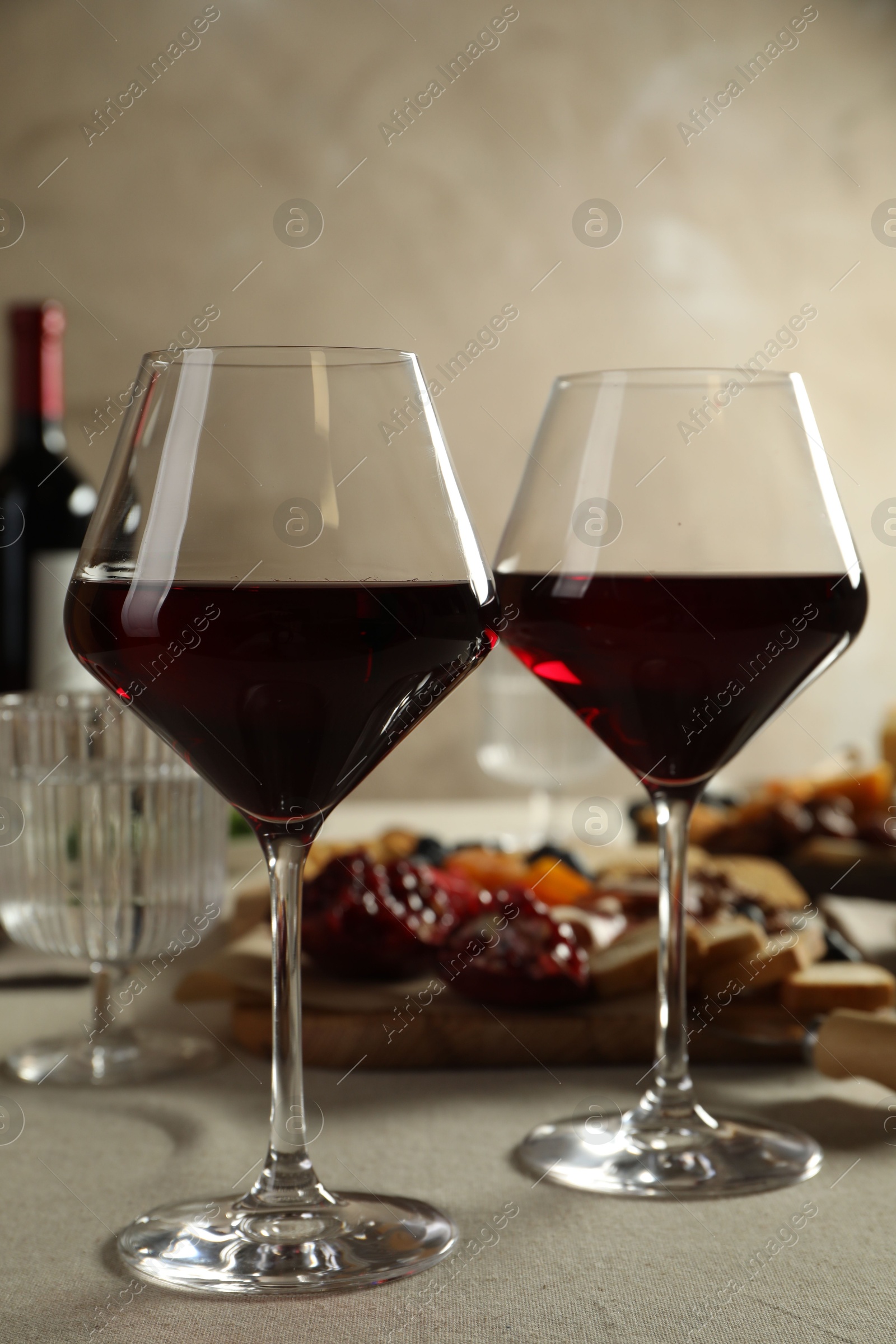 Photo of Red wine and different snacks served on light grey table