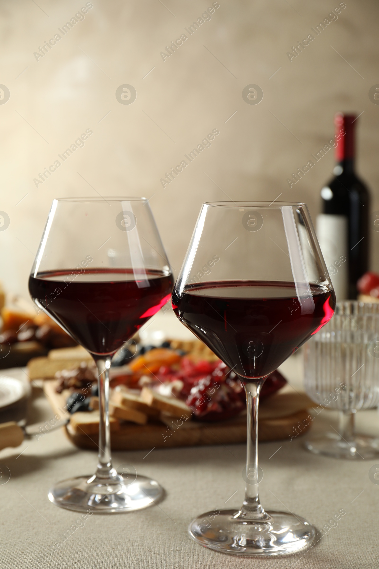 Photo of Red wine and different snacks served on light grey table