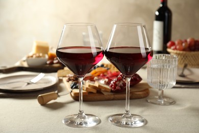 Photo of Red wine and different snacks served on light grey table