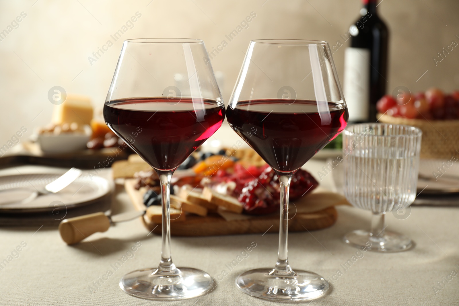 Photo of Red wine and different snacks served on light grey table