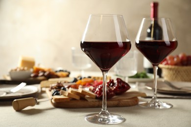 Photo of Red wine and different snacks served on light grey table