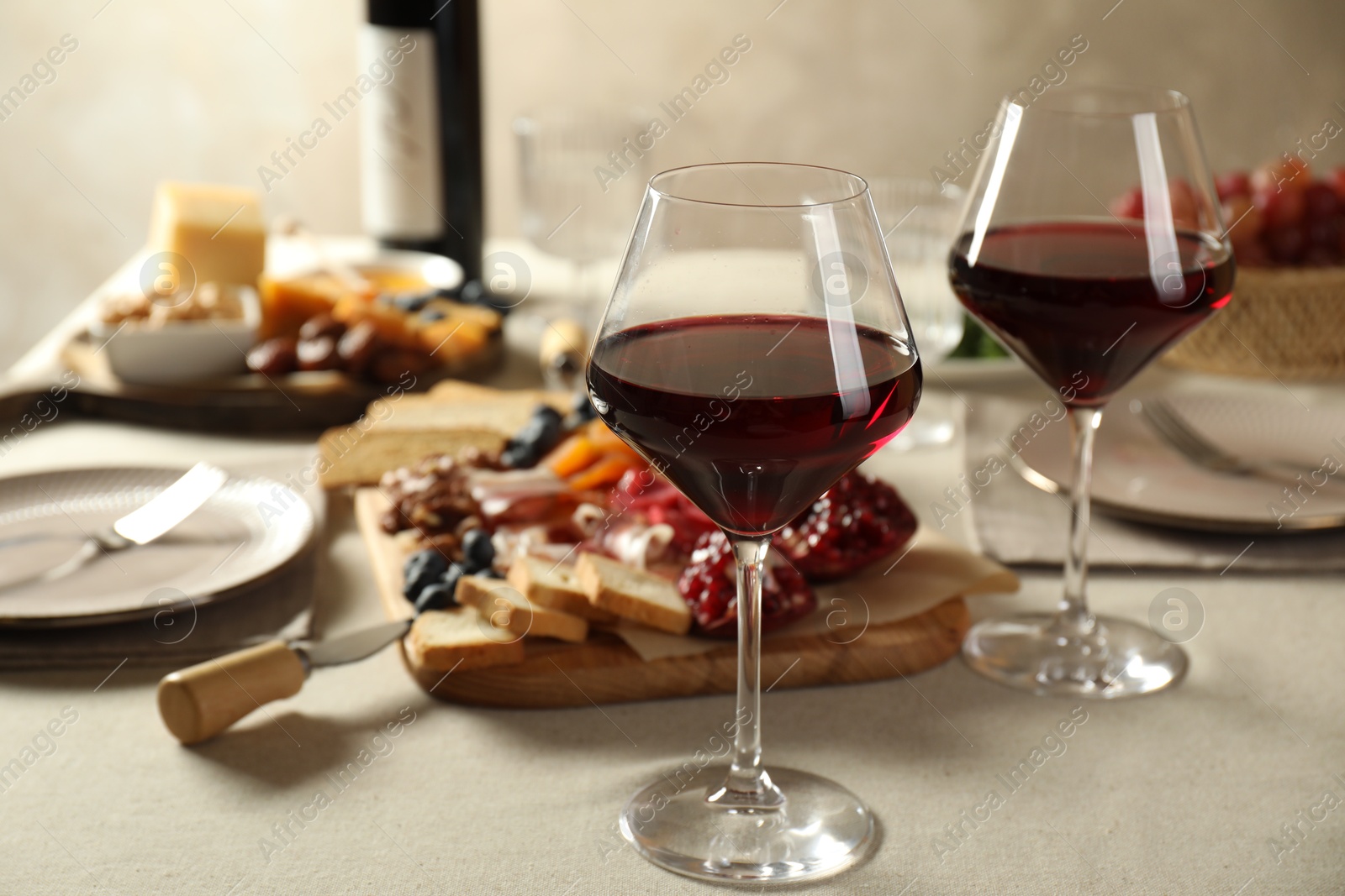 Photo of Red wine and different snacks served on light grey table