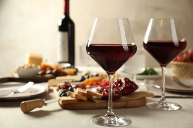 Photo of Red wine and different snacks served on light grey table