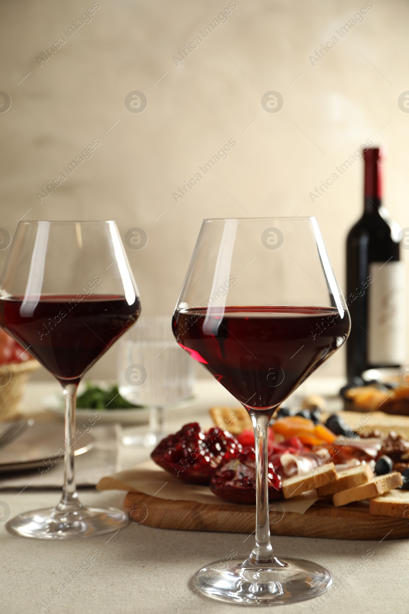 Photo of Red wine and different snacks served on light grey table