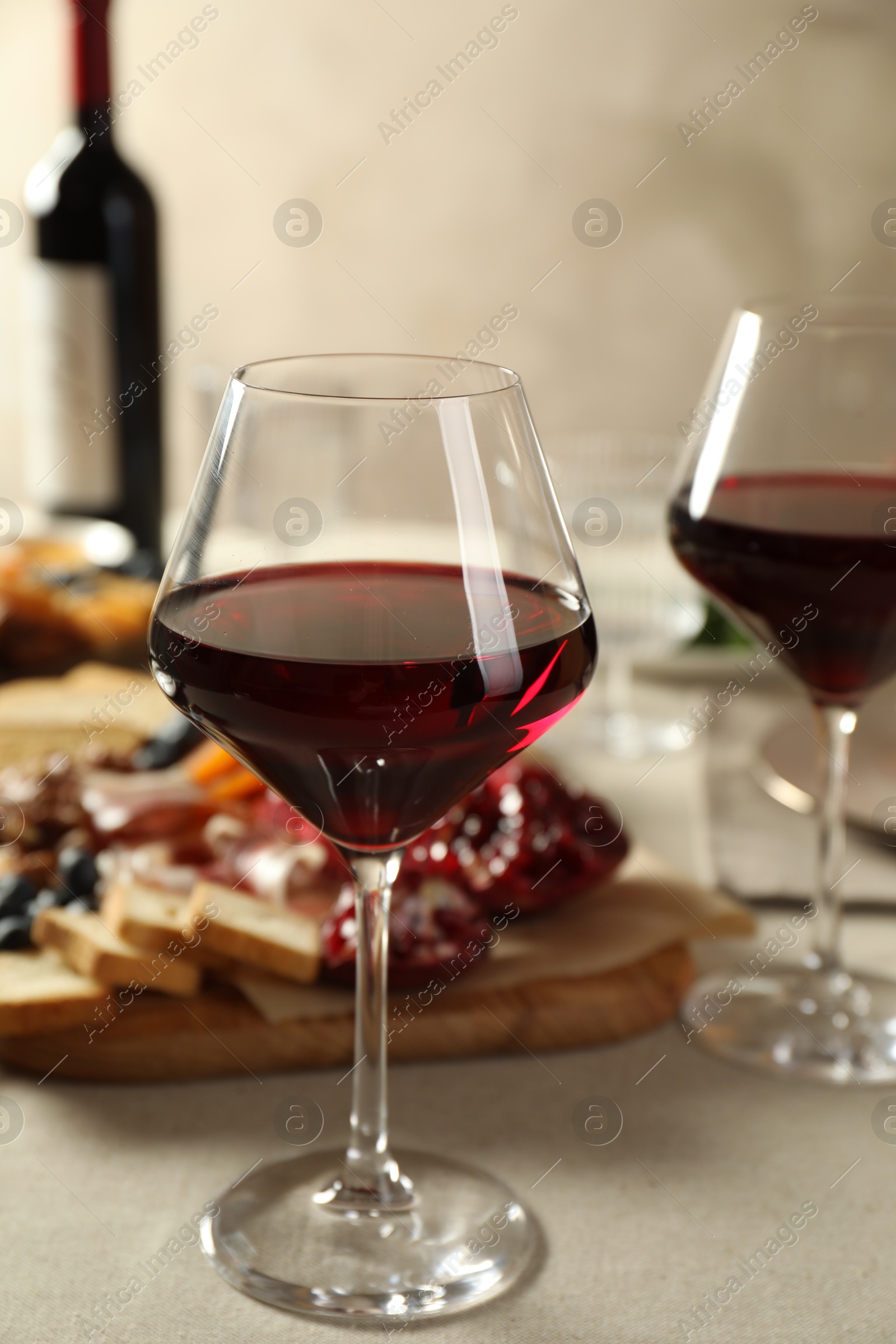 Photo of Red wine and different snacks served on light grey table, closeup