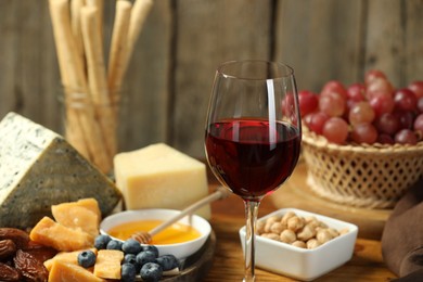 Photo of Red wine and different snacks served on table, closeup