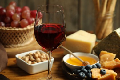 Photo of Red wine and different snacks served on table, closeup