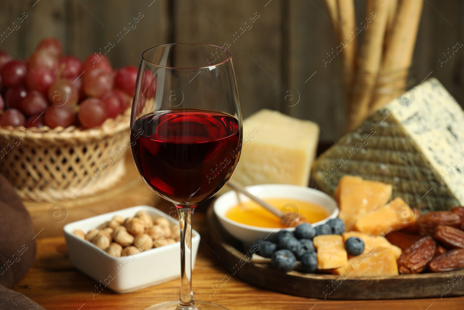 Photo of Red wine and different snacks served on wooden table, closeup