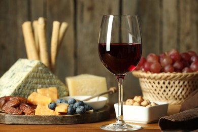 Photo of Red wine and different snacks served on wooden table