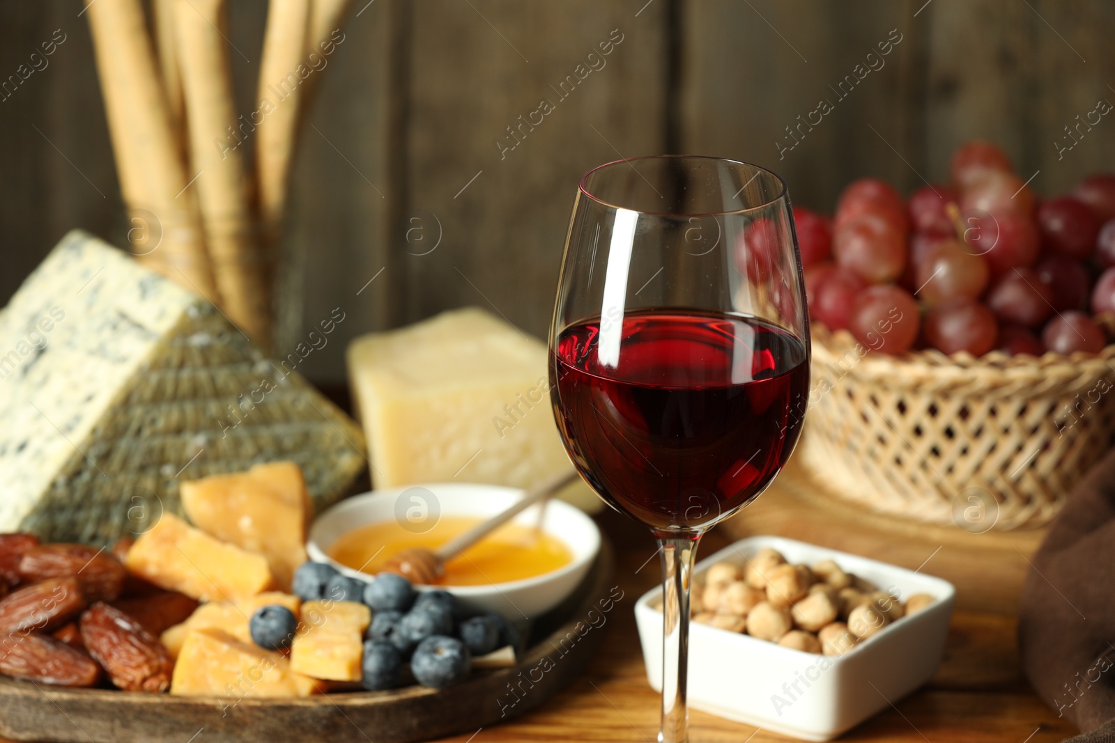 Photo of Red wine and different snacks served on table, closeup