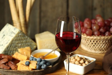 Photo of Red wine and different snacks served on table, closeup