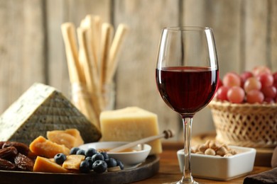 Photo of Red wine and different snacks served on table