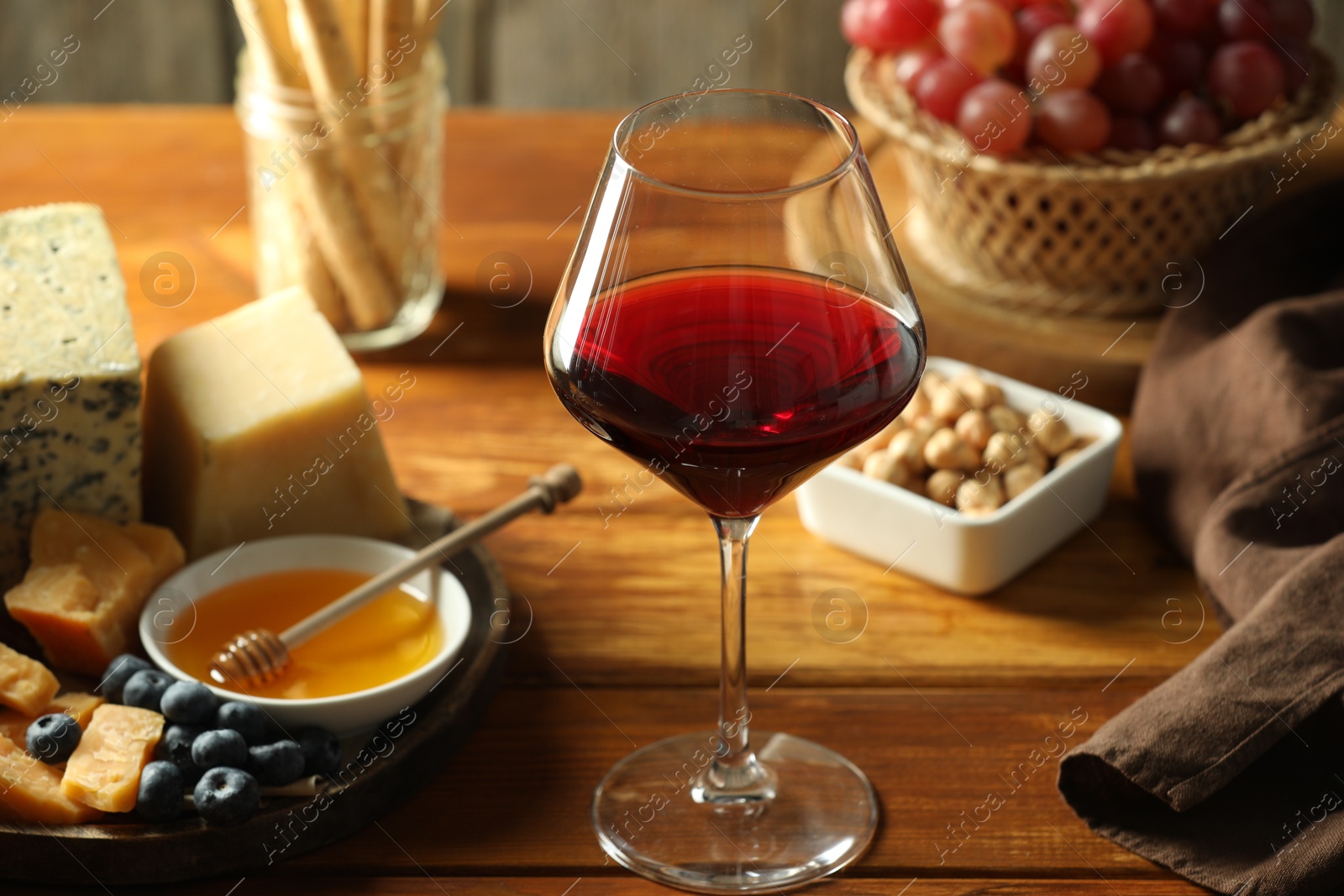 Photo of Red wine and different snacks served on wooden table, closeup