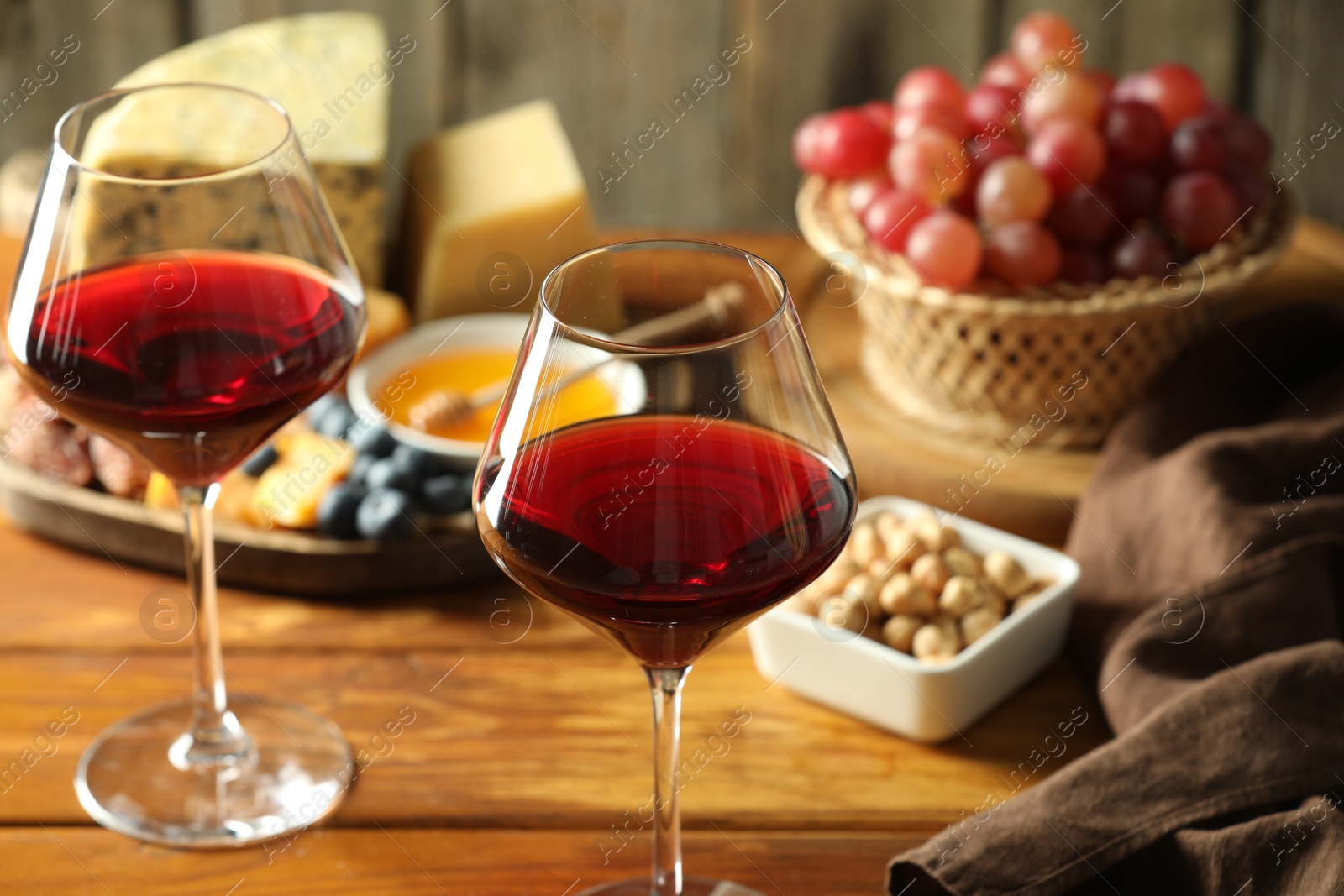 Photo of Red wine and different snacks served on wooden table, closeup