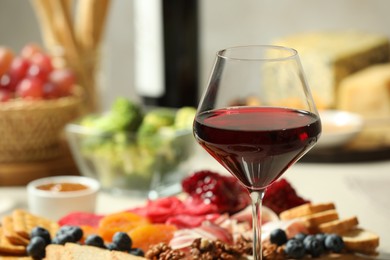 Photo of Red wine and different snacks served on table, closeup