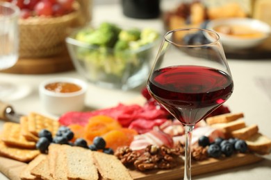 Photo of Red wine and different snacks served on table, closeup