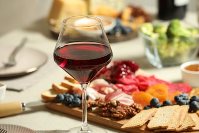 Photo of Red wine and different snacks served on table, closeup