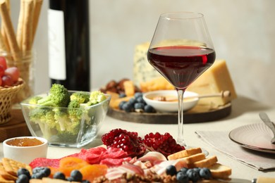 Photo of Red wine and different snacks served on table, closeup