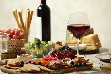 Photo of Red wine and different snacks served on table