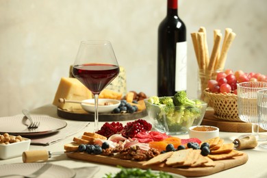 Photo of Red wine and different snacks served on table